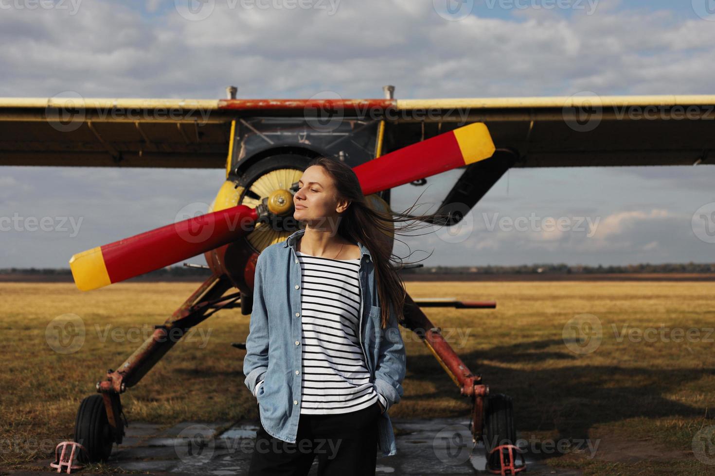 joven y bella mujer de pie cerca del avión. viajes y tecnología. foto