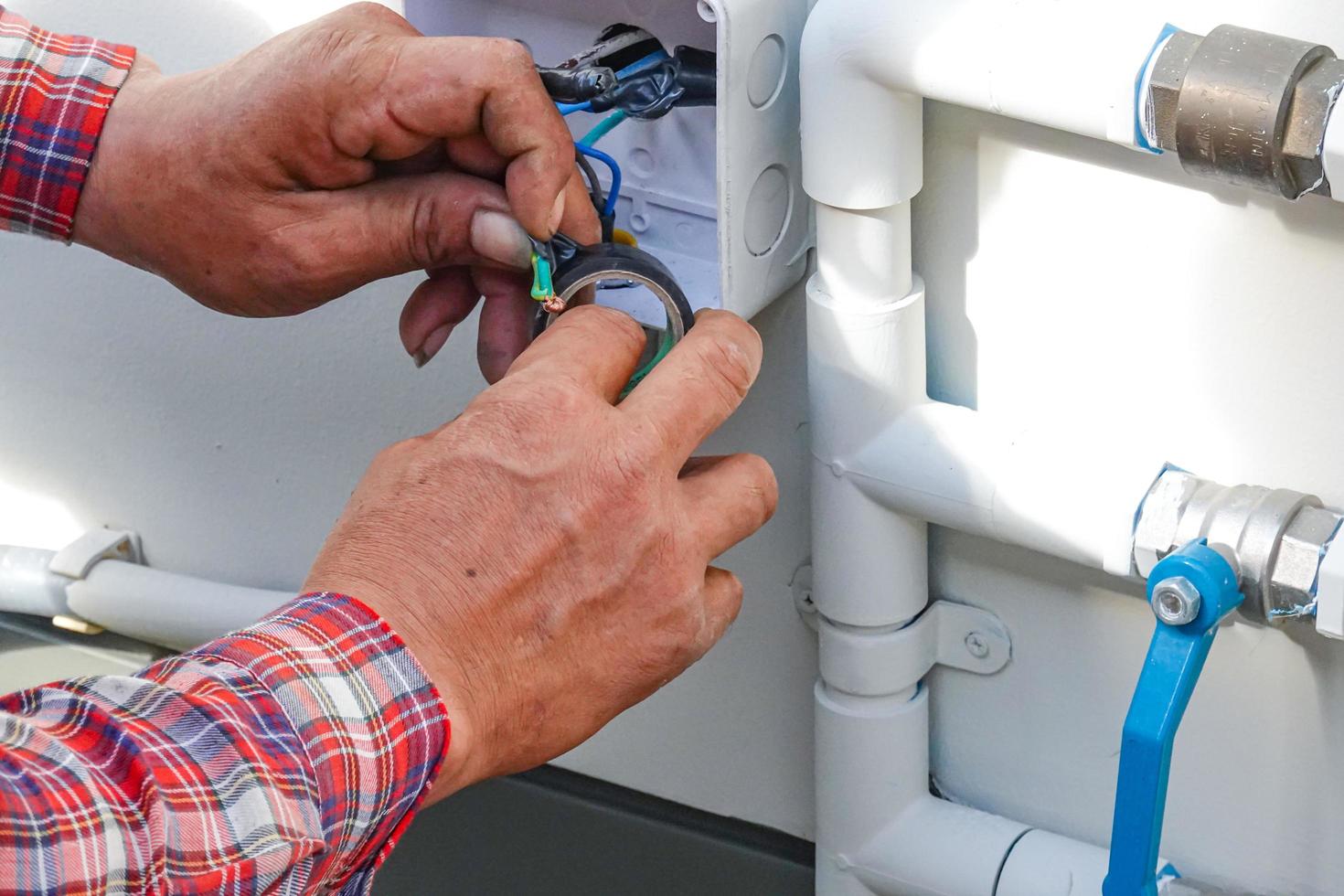 Electricista reparar cable de alimentación para control de bomba de agua en el sitio de casa. foto