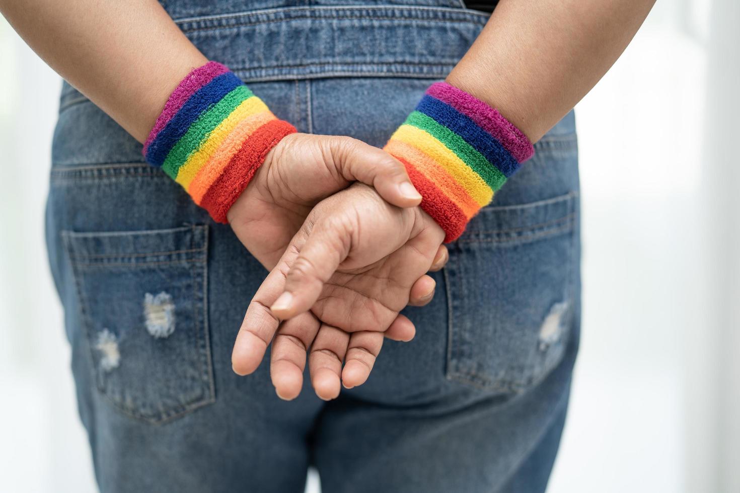 dama asiática con pulseras de la bandera del arco iris, símbolo del mes del orgullo lgbt celebran anualmente en junio las redes sociales de gays, lesbianas, bisexuales, transgénero, derechos humanos. foto