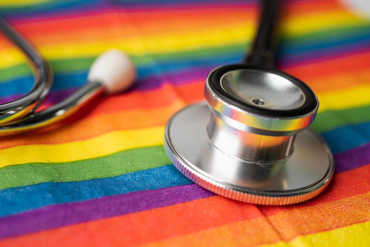 Black stethoscope on rainbow flag background, symbol of LGBT pride month celebrate annual in June social, symbol of gay, lesbian, bisexual, transgender, human rights and peace. photo