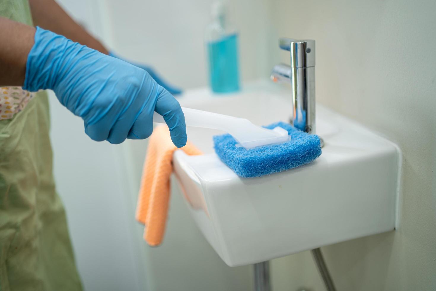 Maid cleaning wash and scrub basin in toilet at home. photo