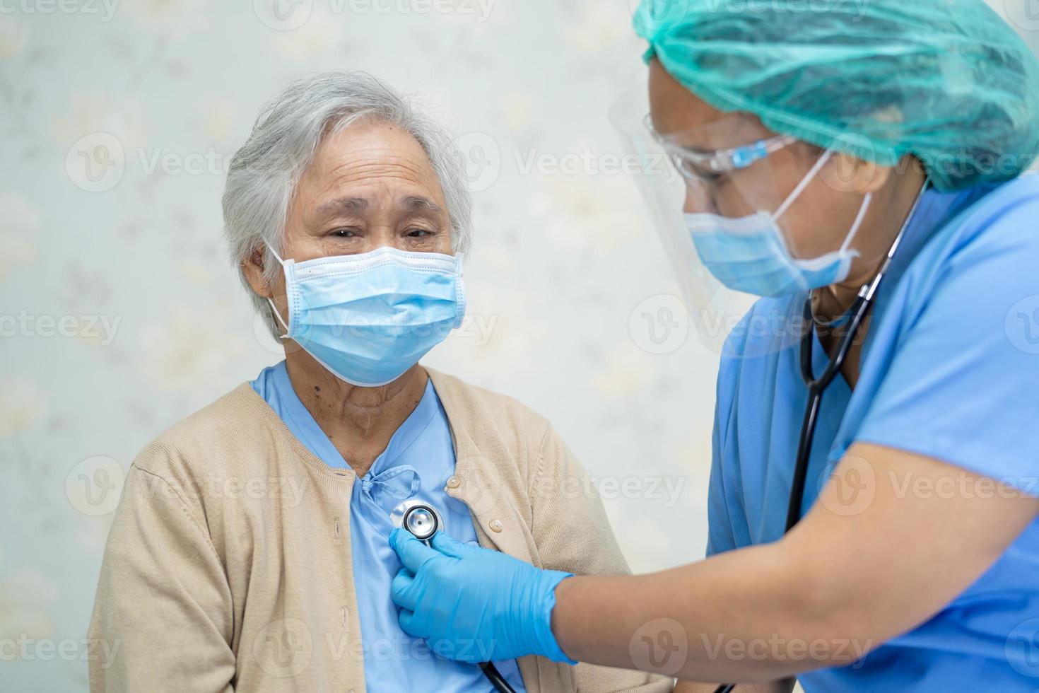 Doctor using stethoscope to checking Asian senior or elderly old lady woman patient wearing a face mask in hospital for protect infection Covid-19 Coronavirus. photo