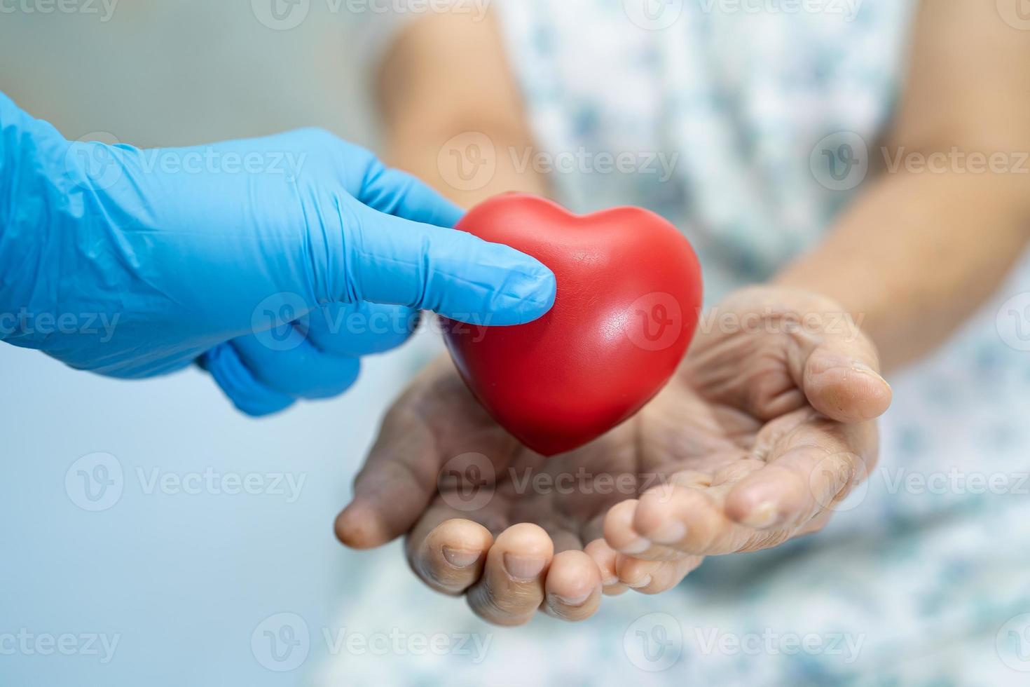 Doctor give red heart to Asian senior or elderly old lady woman patient, healthy strong medical concept photo