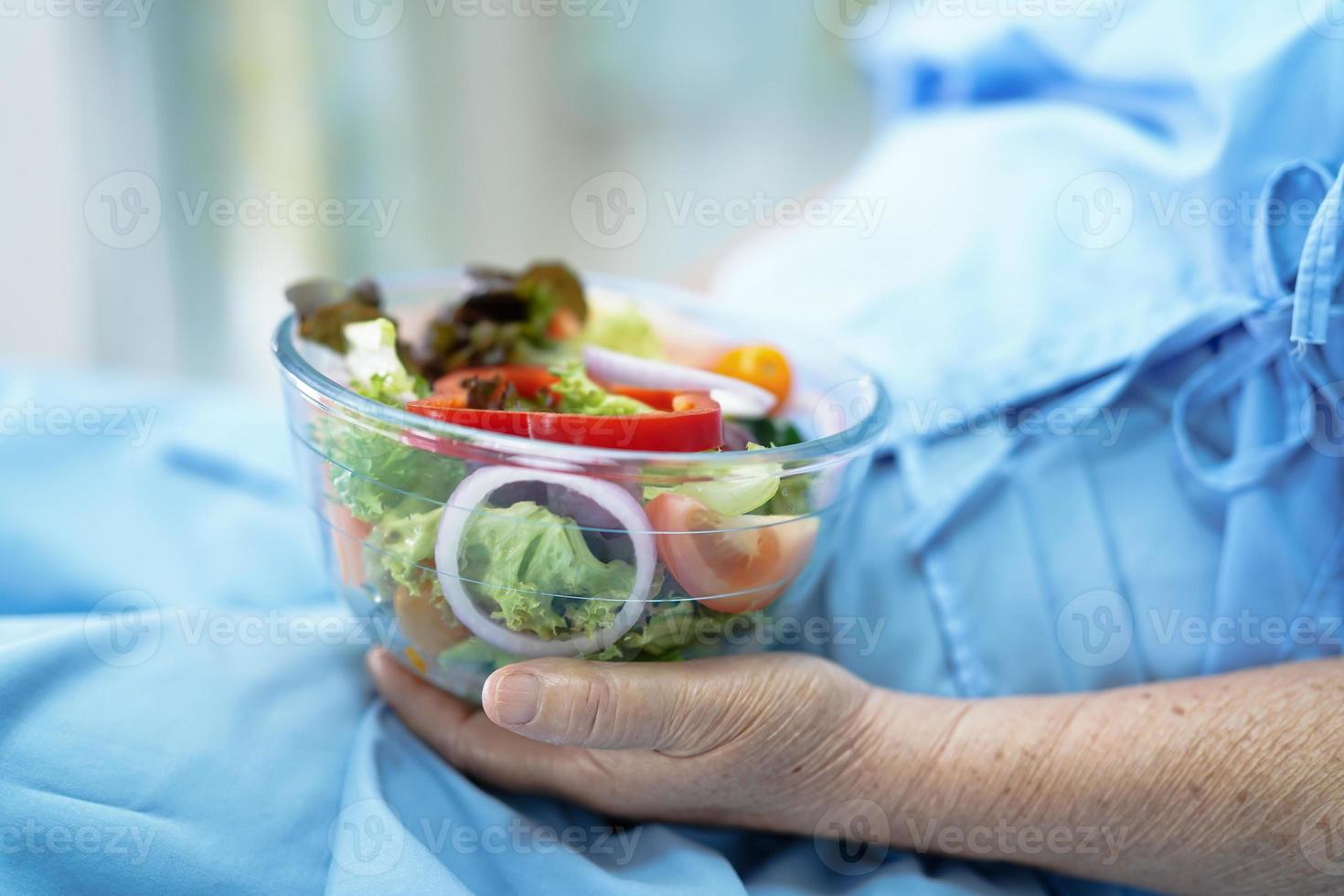 Paciente asiático mayor o anciano mujer desayunando vegetales alimentos saludables con esperanza y feliz mientras está sentado y hambriento en la cama en el hospital. foto