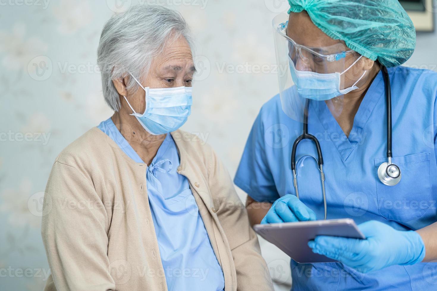 Asian doctor wearing face shield and PPE suit new normal to check patient protect safety infection Covid-19 Coronavirus outbreak at quarantine nursing hospital ward. photo