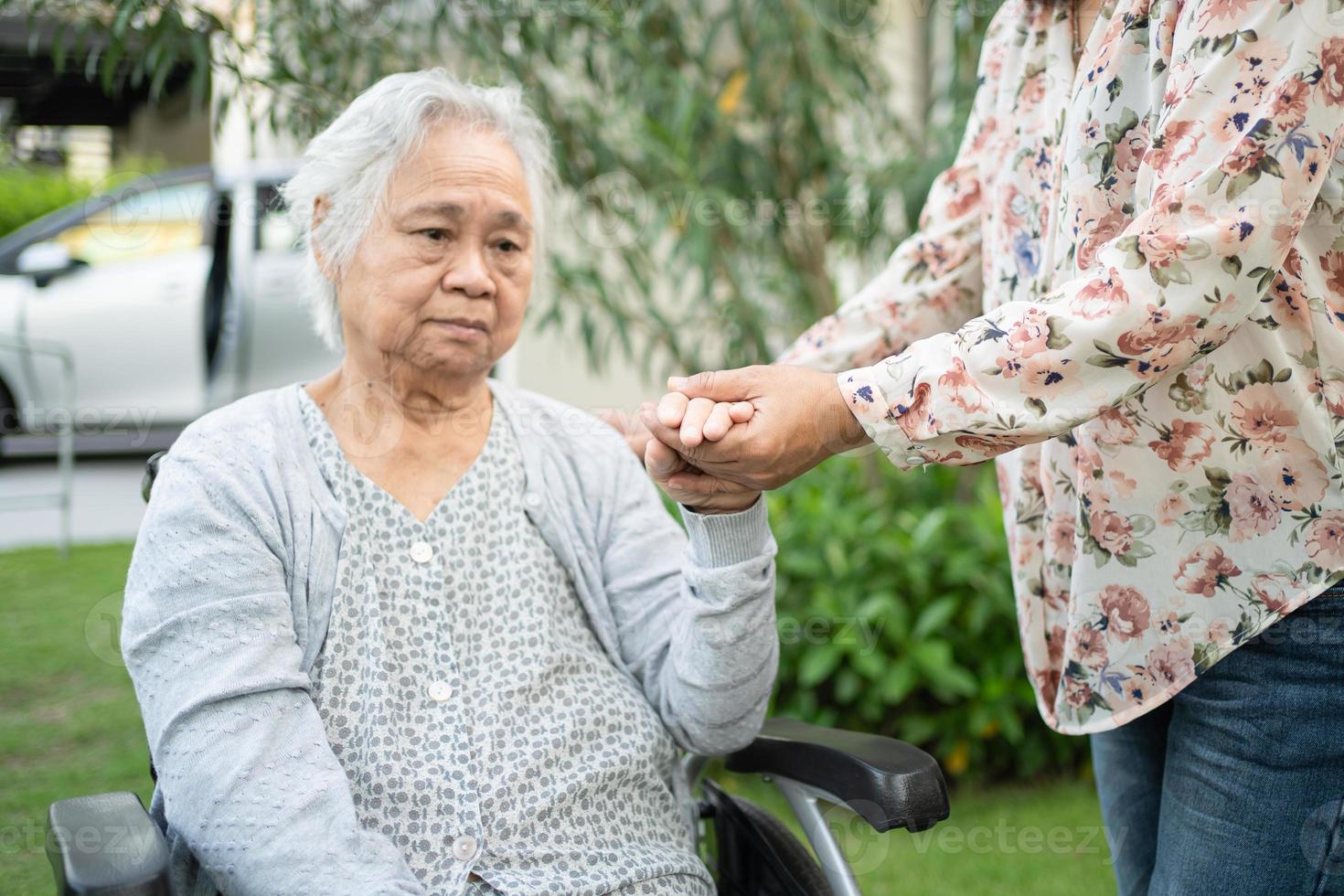 Help Asian senior or elderly old lady woman on wheelchair and wearing a face mask for protect safety infection Covid-19 Coronavirus in park. photo