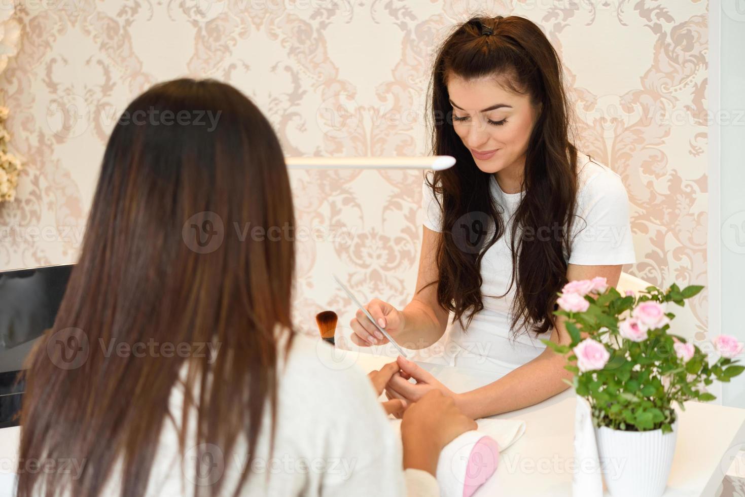 cuidado de las uñas de manicura para el cliente sentado en una mesa en la oficina. foto