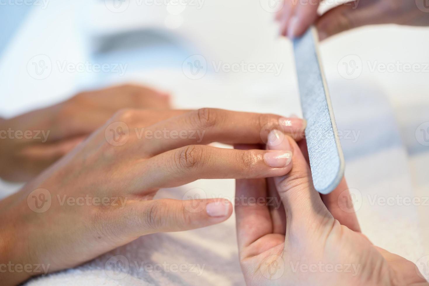 Mujer en un salón de uñas recibiendo una manicura con lima de uñas foto