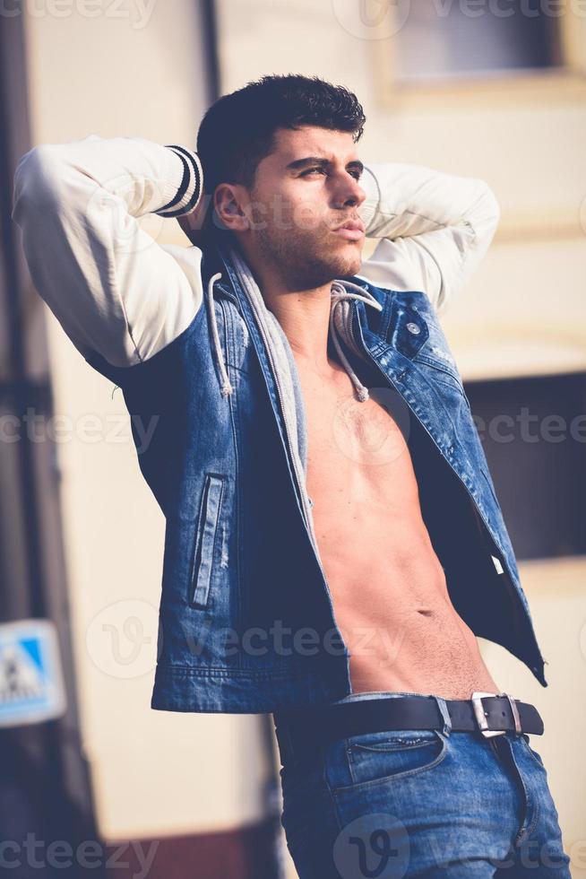 Handsome young man with blue eyes posing in urban background photo