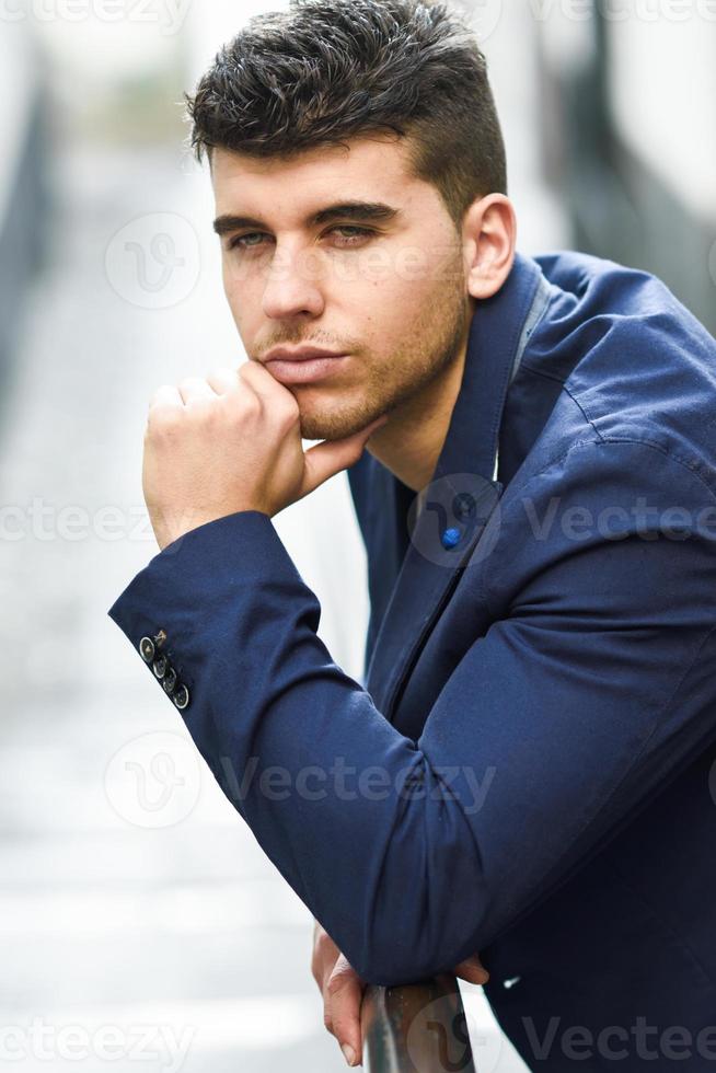 joven guapo con ojos azules posando cerca de una pared foto