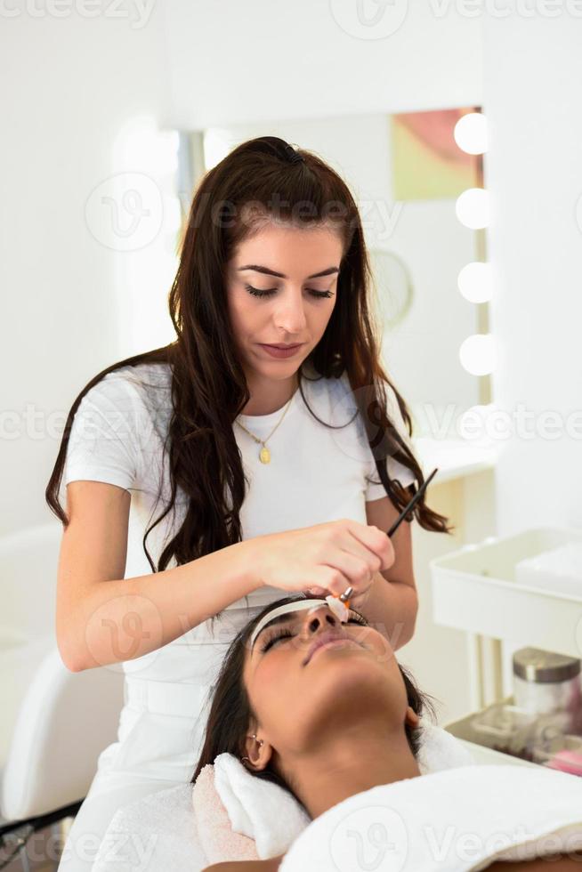 estética aplicando una máscara al rostro de una mujer hermosa foto