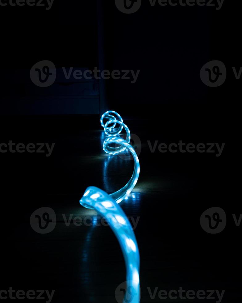 blue glowing LED strip with cold light on a black background close-up, decorative lighting photo