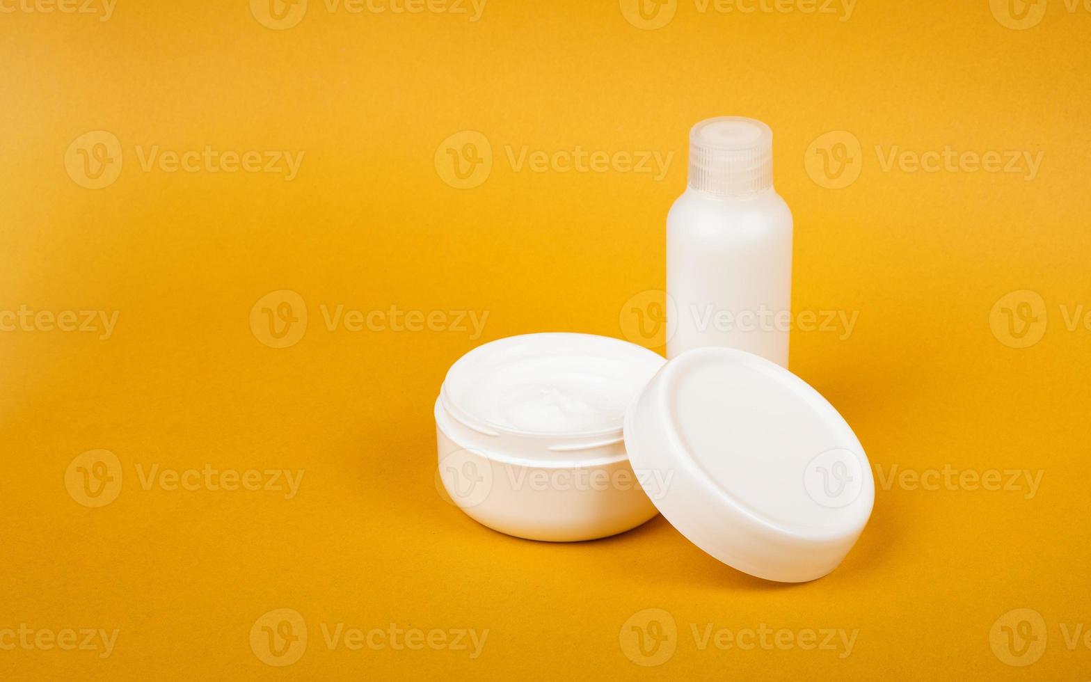 Botella cosmética blanca y crema con espacio de copia sobre fondo amarillo belleza cuidado de la piel foto