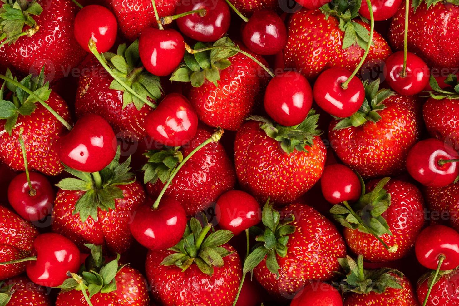 Fondo fresco, fresas y cerezas recién cosechadas, fondo con bayas y frutas de temporada foto