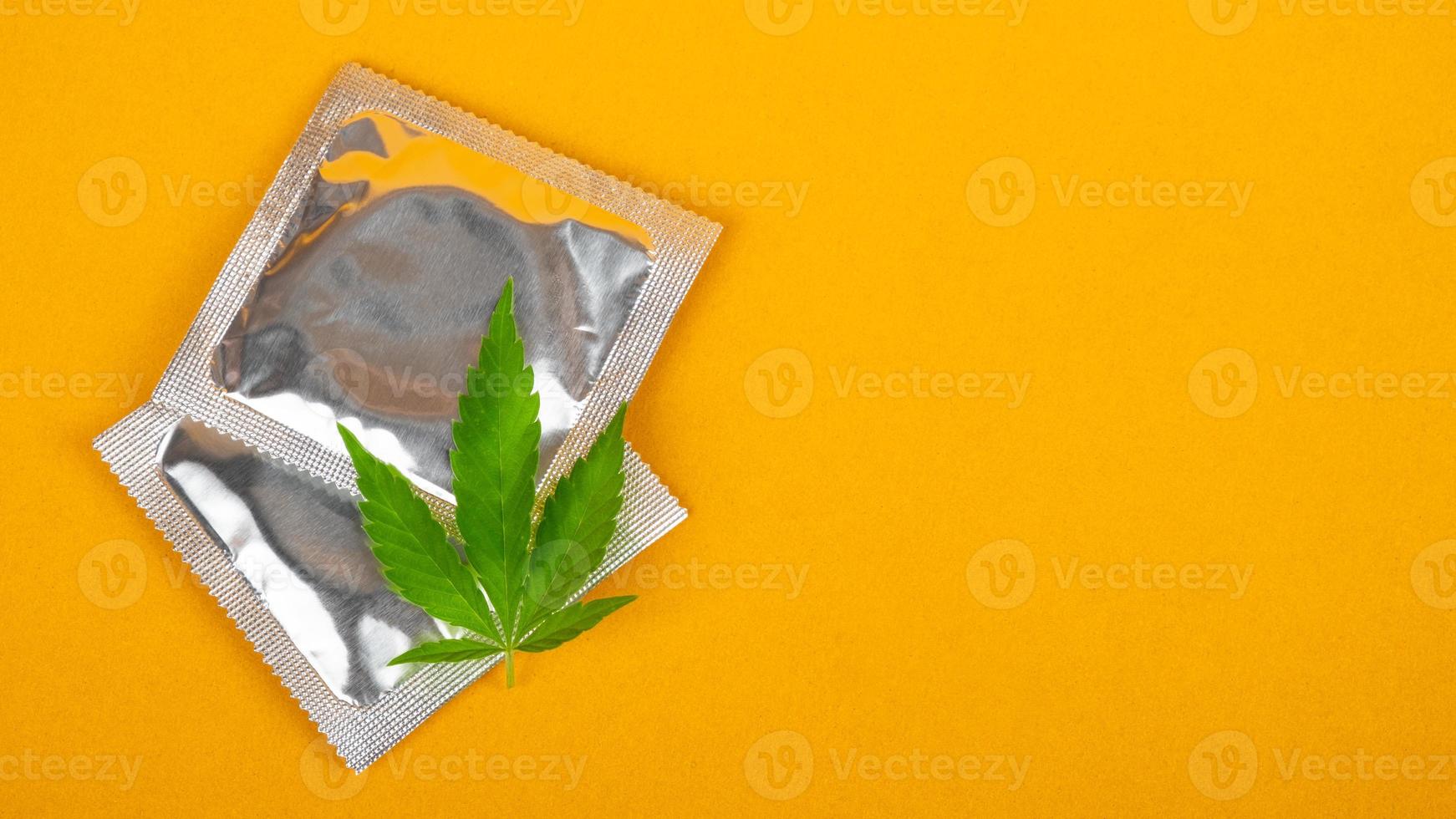 condom and cannabis leaf with copy space on yellow background, sex drugs mockup photo