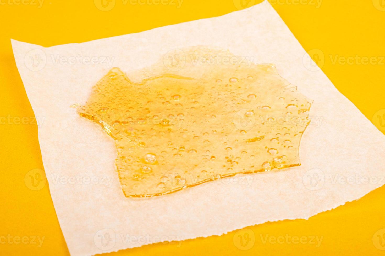 Extracto de cera de marihuana con alto thc sobre papel pergamino sobre fondo amarillo foto