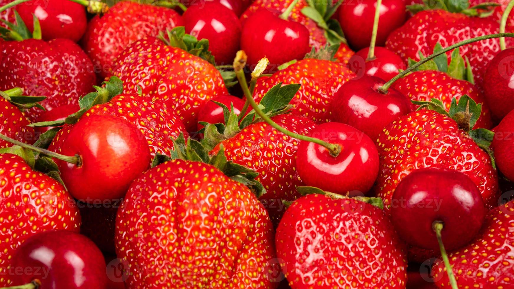 Cereza dulce y fresas sobre un fondo rojo closeup foto