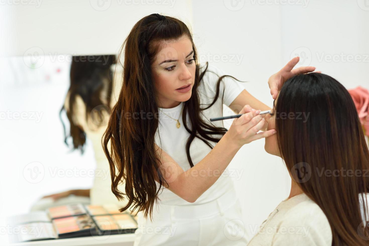 Make-up artist putting eye shadow on an African woman. in a beauty center. photo