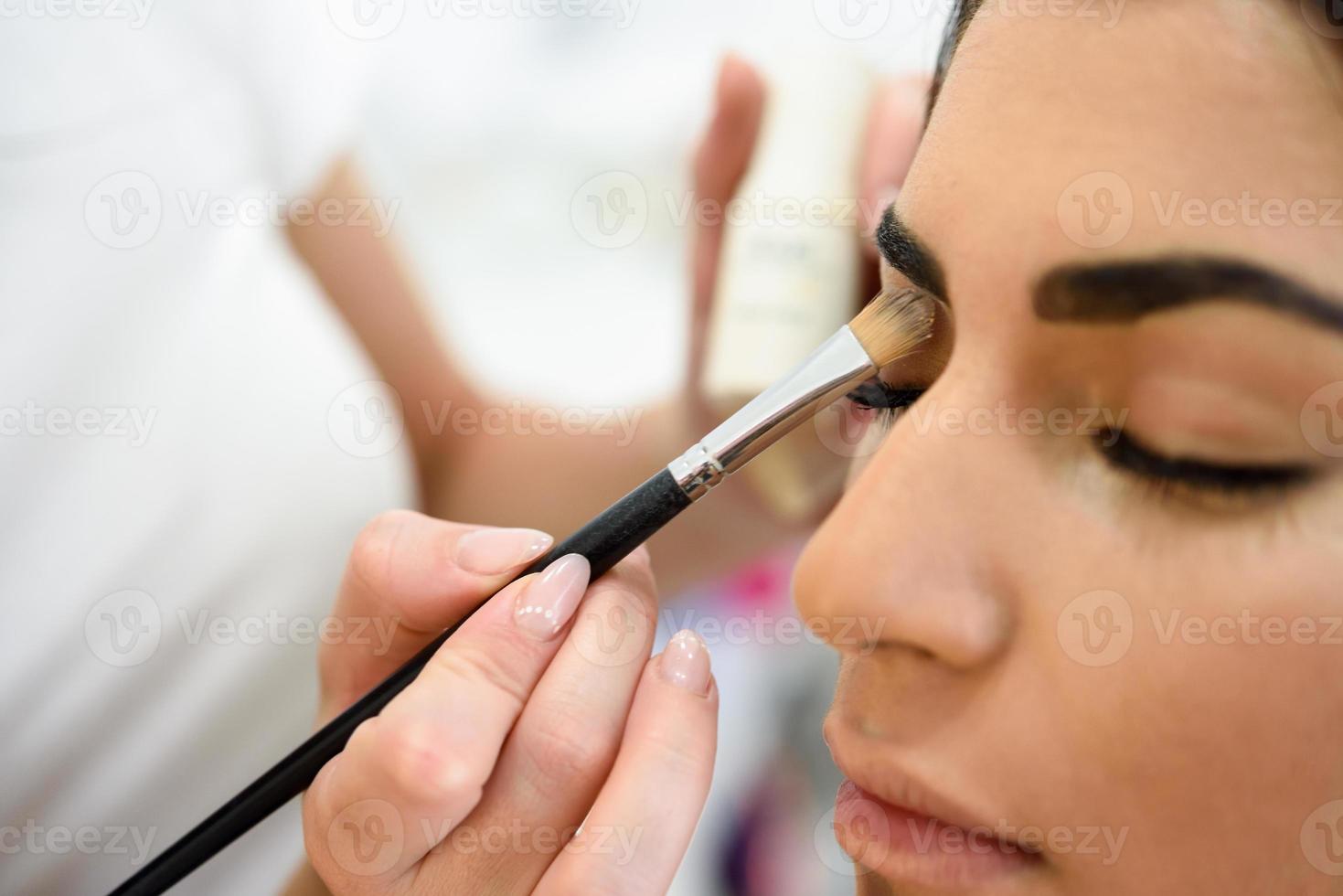 maquilladora poniendo sombra de ojos en una mujer africana. foto