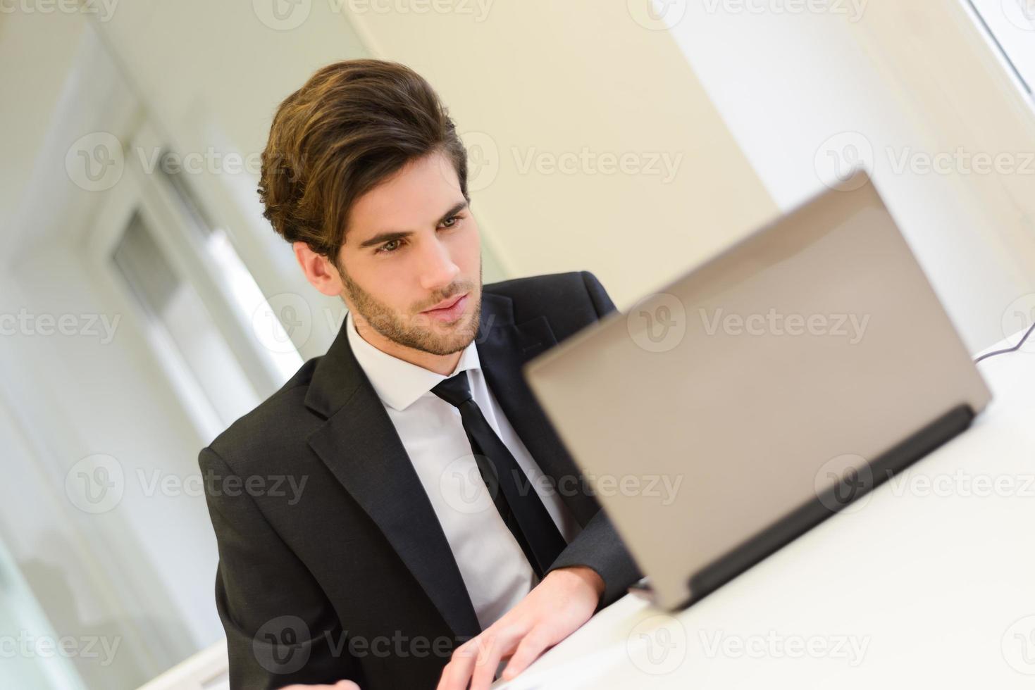 empresario sentado en su computadora portátil y trabajando en su oficina foto