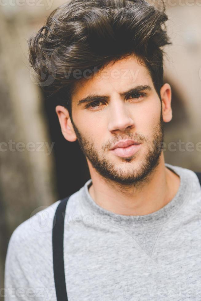 Young man wearing suspenders in urban background photo