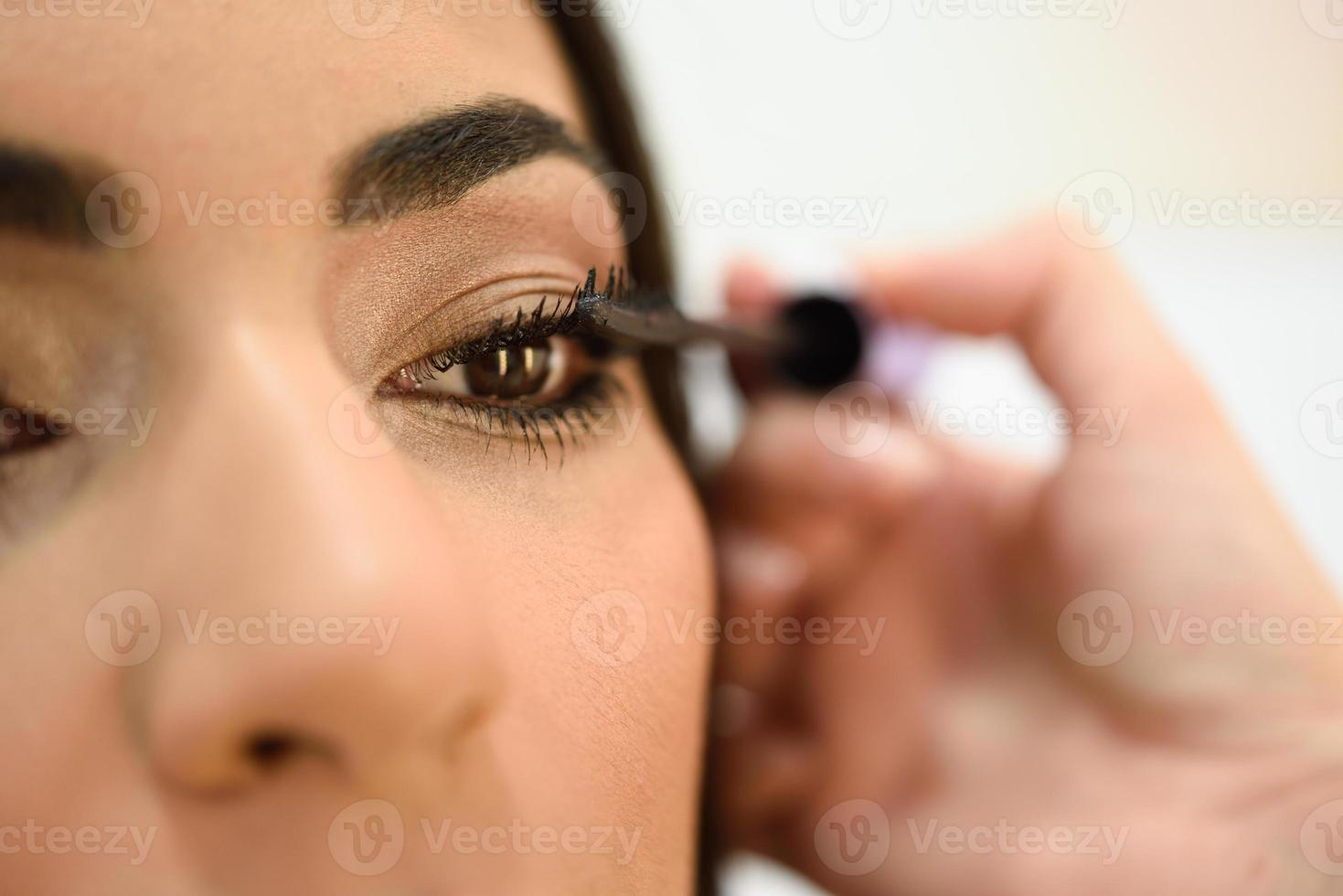 Maquilladora poniéndose las pestañas de una mujer africana foto