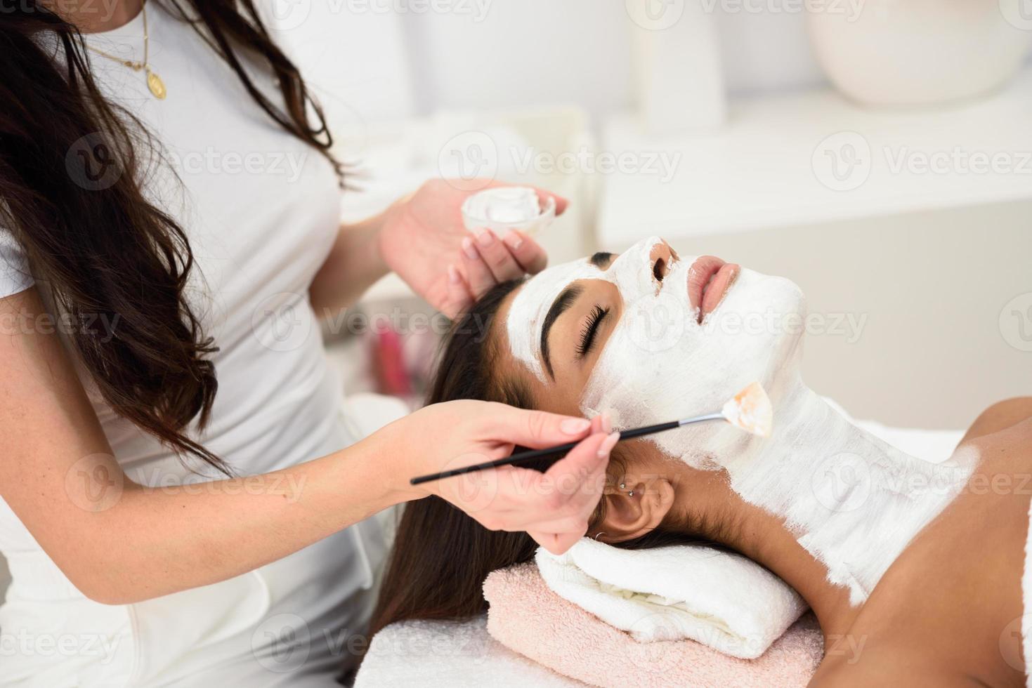 Aesthetics applying a mask to the face of a beautiful woman photo