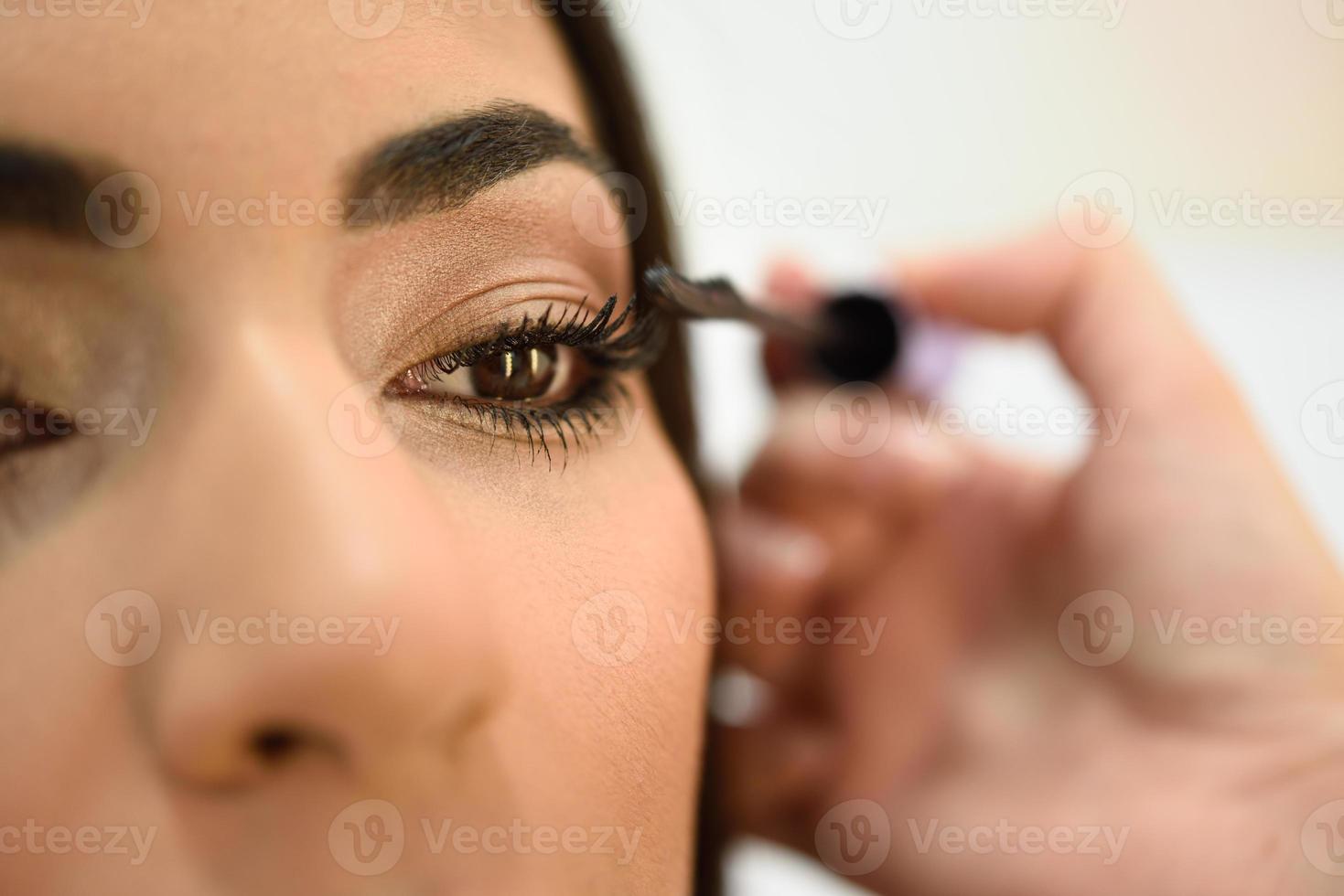 Make-up artist putting on the eyelashes of an African woman photo