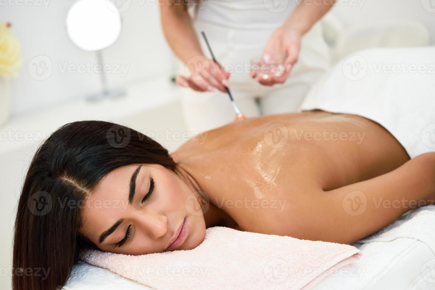 Mujer recibiendo tratamiento de masaje de espalda con cepillo de aceite en el centro de bienestar y spa foto