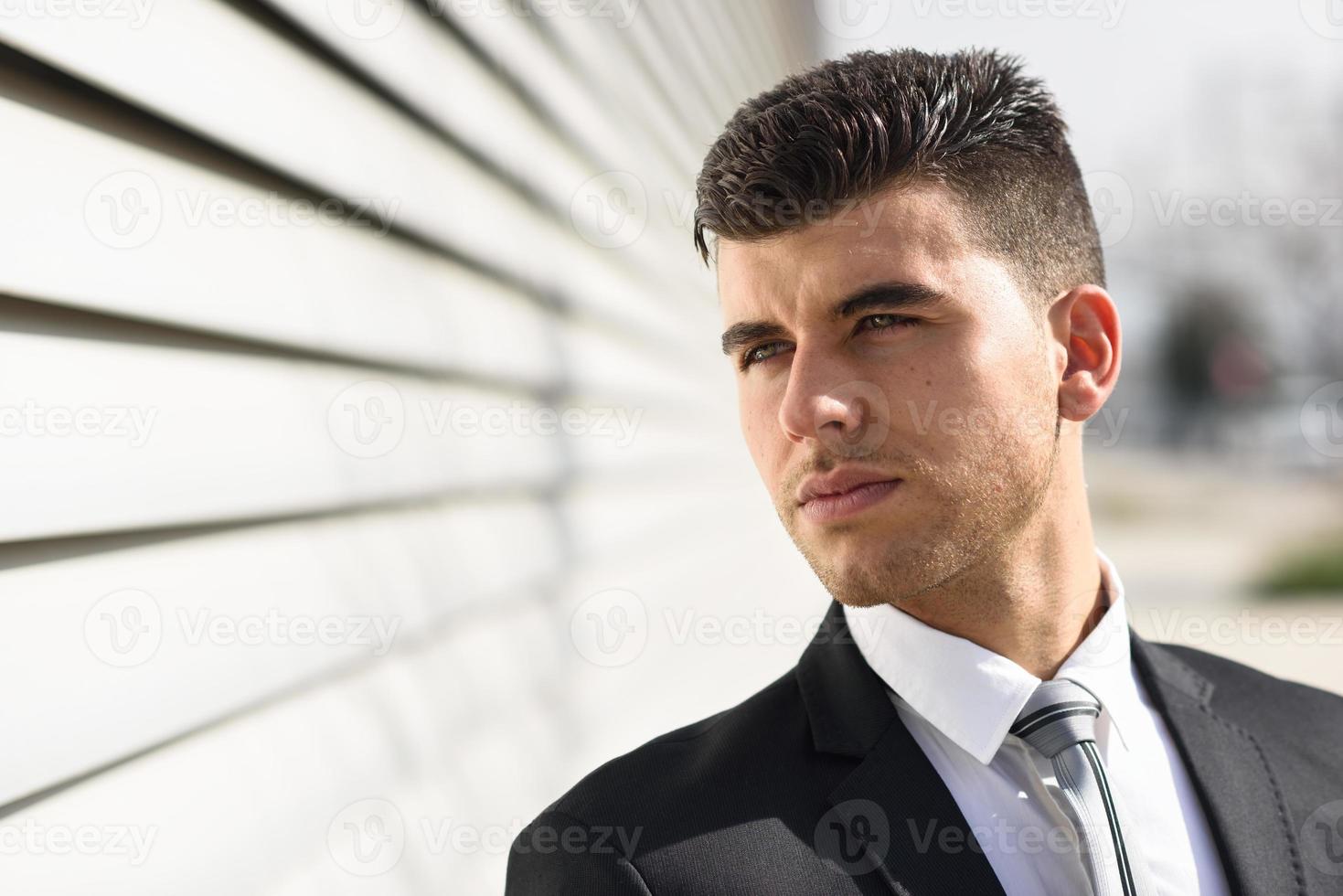 Young businessman near an office building wearing black suit photo