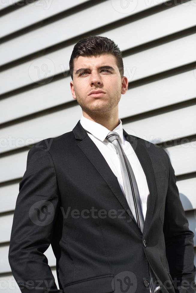 Young businessman near an office building wearing black suit photo