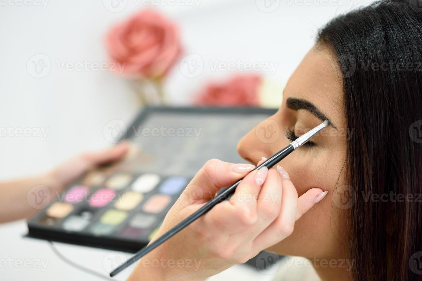 Makeup artist putting make-up on a woman's eyebrows photo