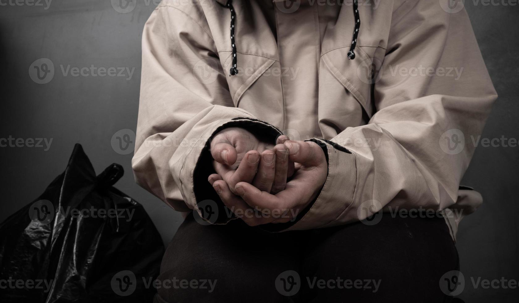 a beggar with outstretched hands asks for money sits on the floor. photo