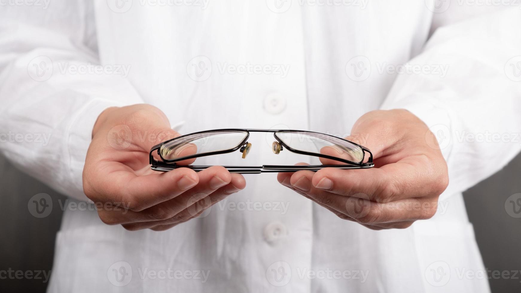 doctor ophthalmologist holding glasses, crutches for eyes photo