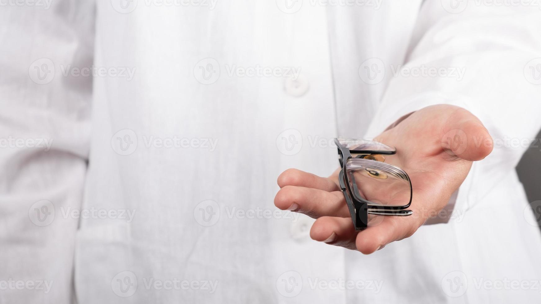 Oftalmólogo sosteniendo anteojos en sus manos de cerca, optometrista profesional ofrece anteojos al paciente foto