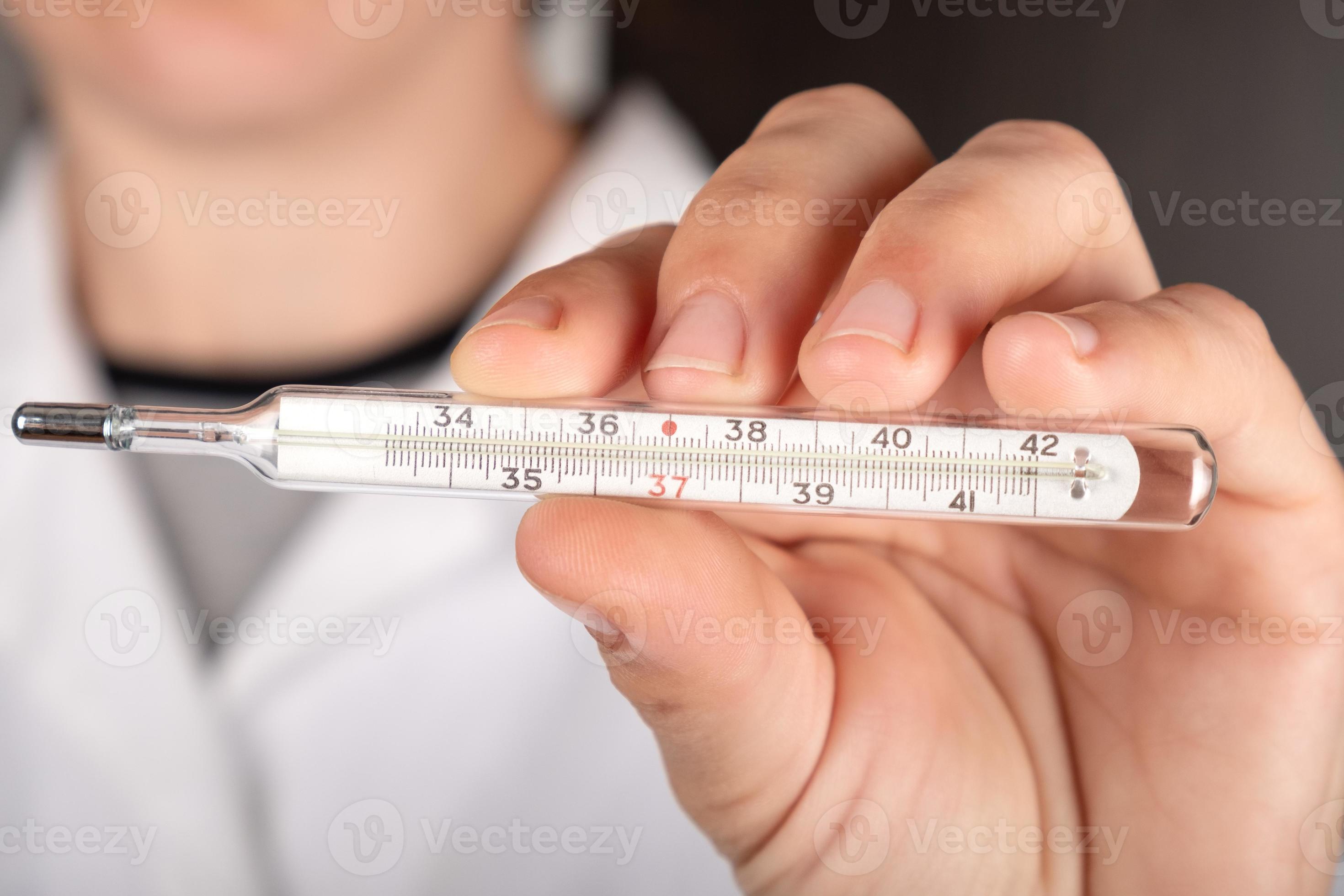 the doctor holds a mercury thermometer in his hand closeup, diagnosis