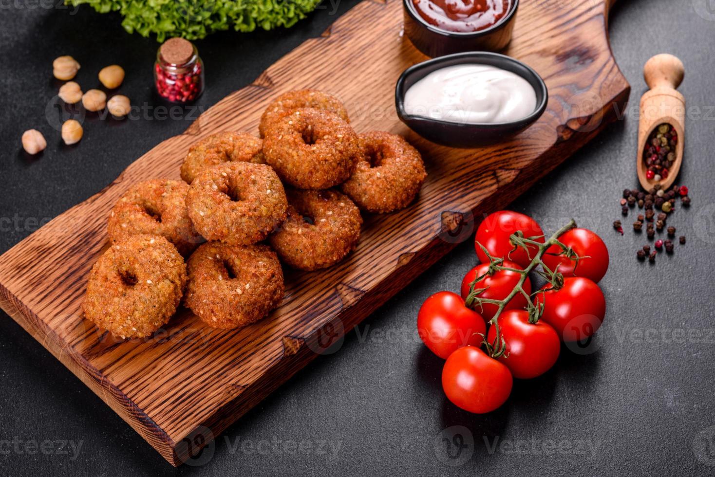 Hermoso delicioso falafel de garbanzos frescos con salsas sobre un fondo de hormigón foto