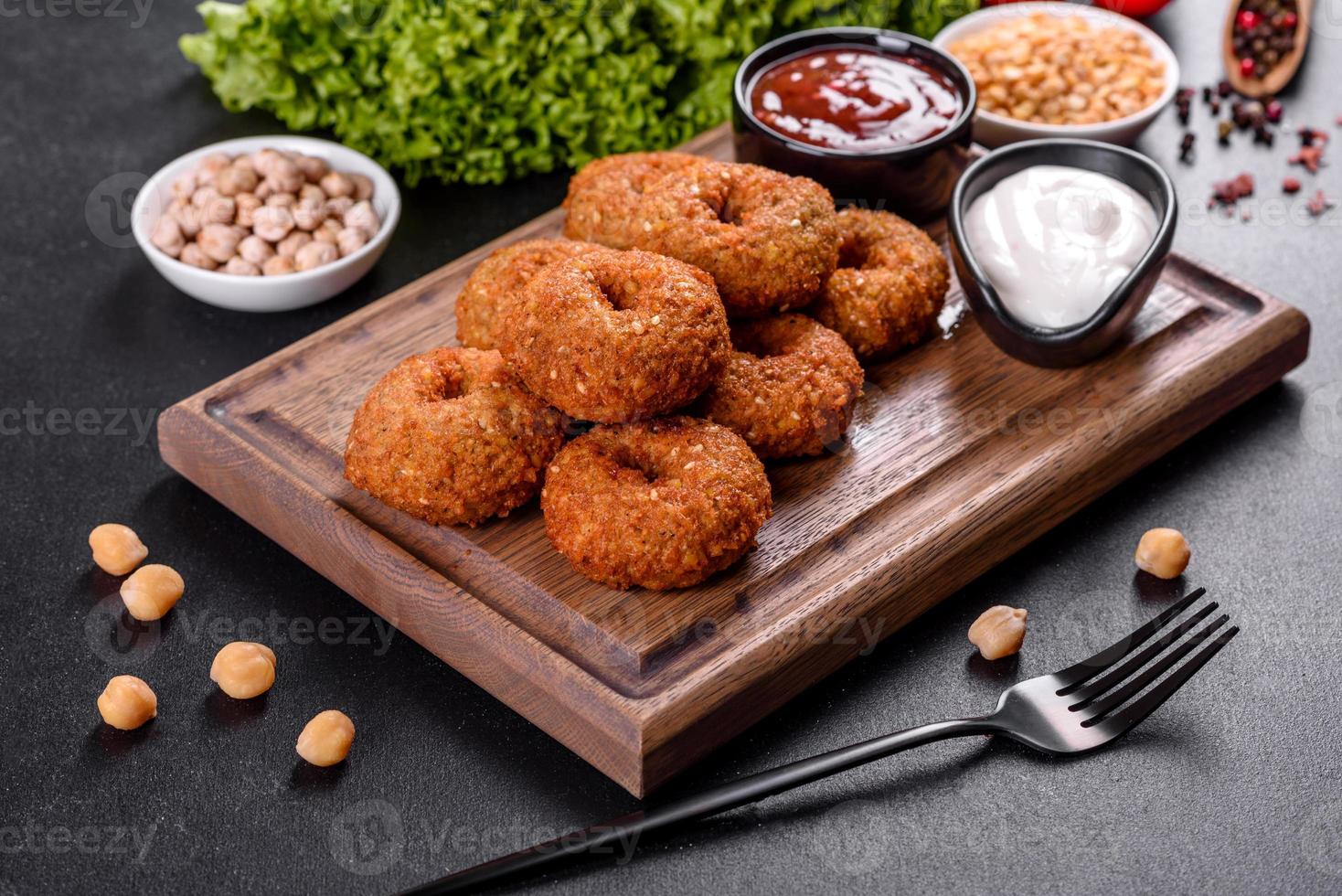 Hermoso delicioso falafel de garbanzos frescos con salsas sobre un fondo de hormigón foto