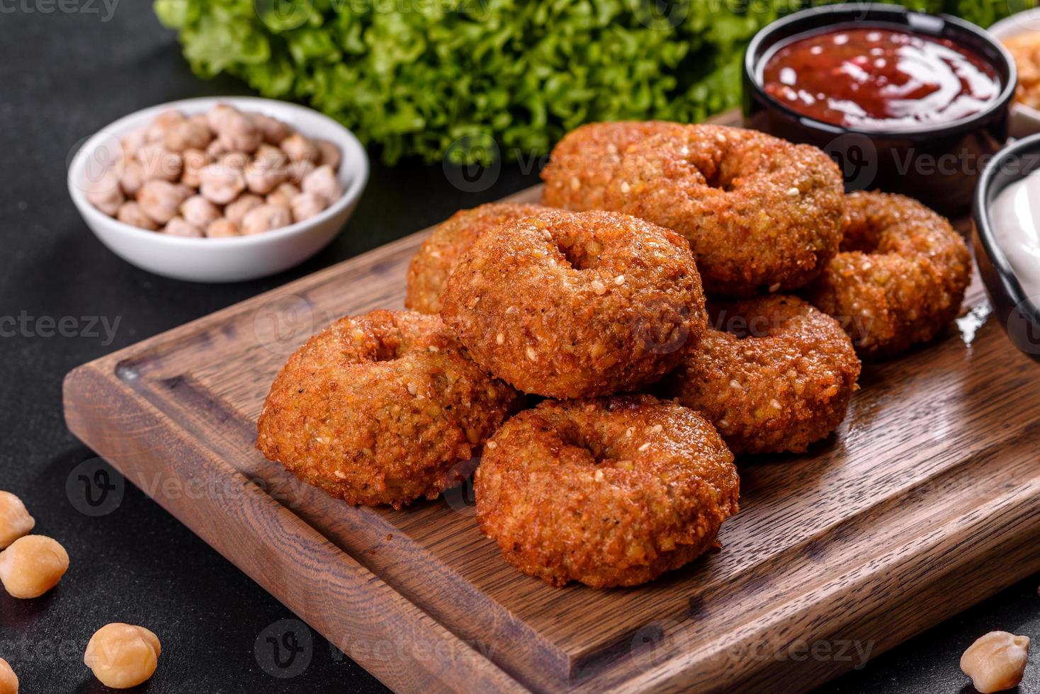 Hermoso delicioso falafel de garbanzos frescos con salsas sobre un fondo de hormigón foto