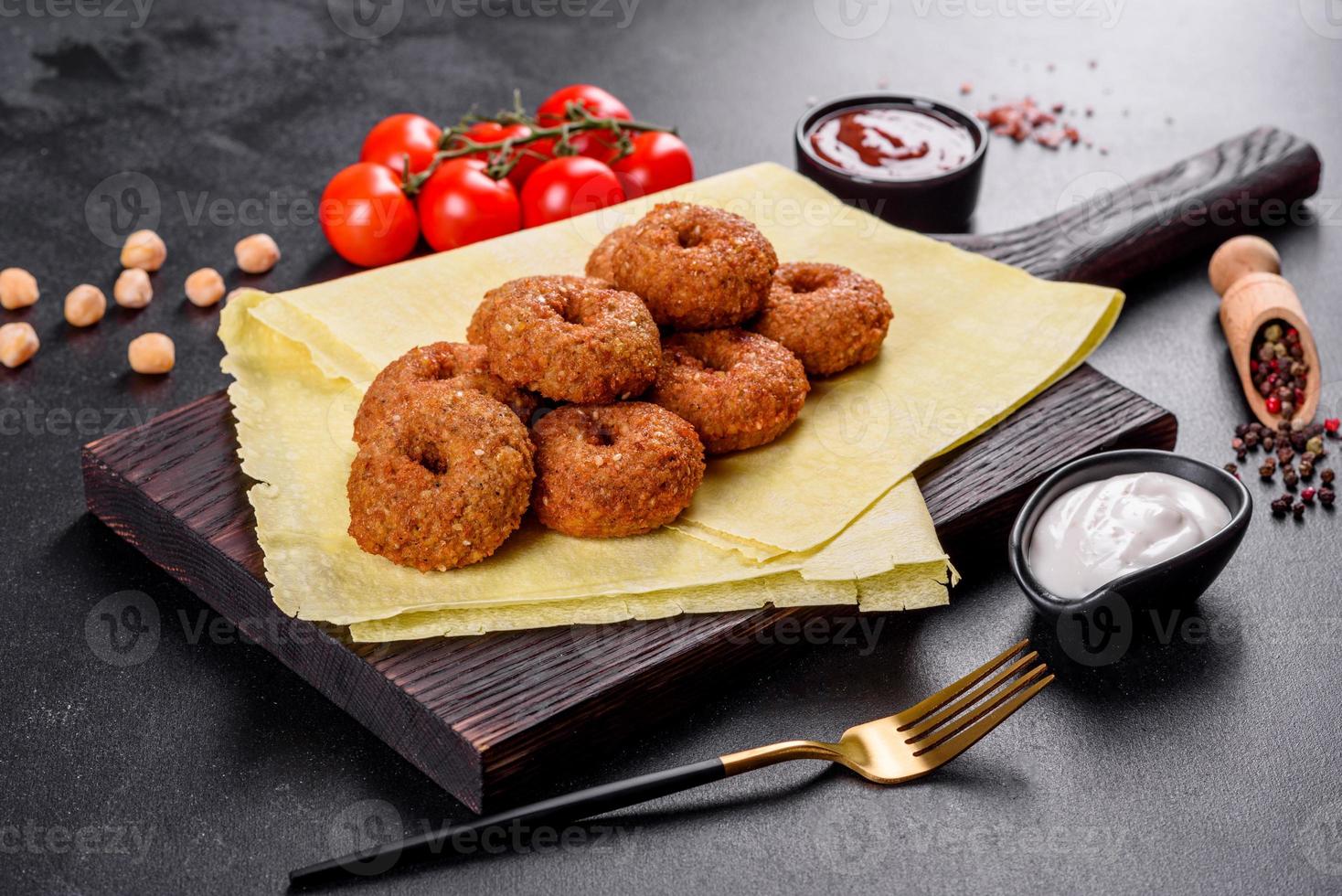 Hermoso delicioso falafel de garbanzos frescos con salsas sobre un fondo de hormigón foto