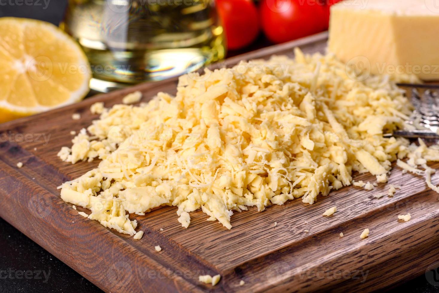 Fresh hard cheese grated on a large grater on a wooden cutting board photo