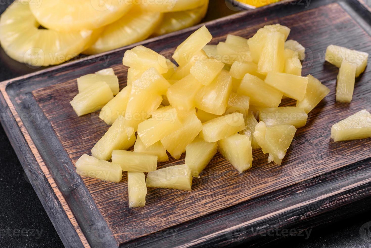 Piña enlatada con trozos sobre una tabla de cortar de madera foto