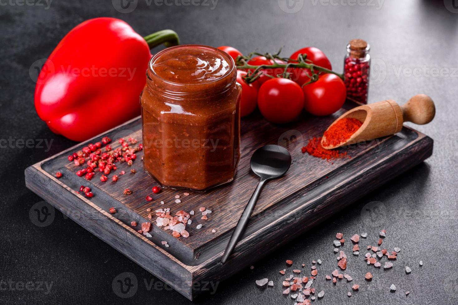 condimento picante de la cocina georgiana adjika en un recipiente con pimiento rojo y ajo foto