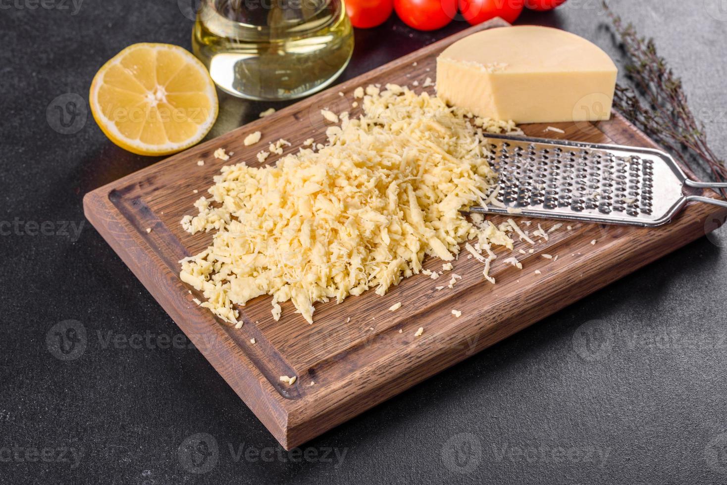 Queso duro fresco rallado en un rallador grande sobre una tabla de cortar de madera foto