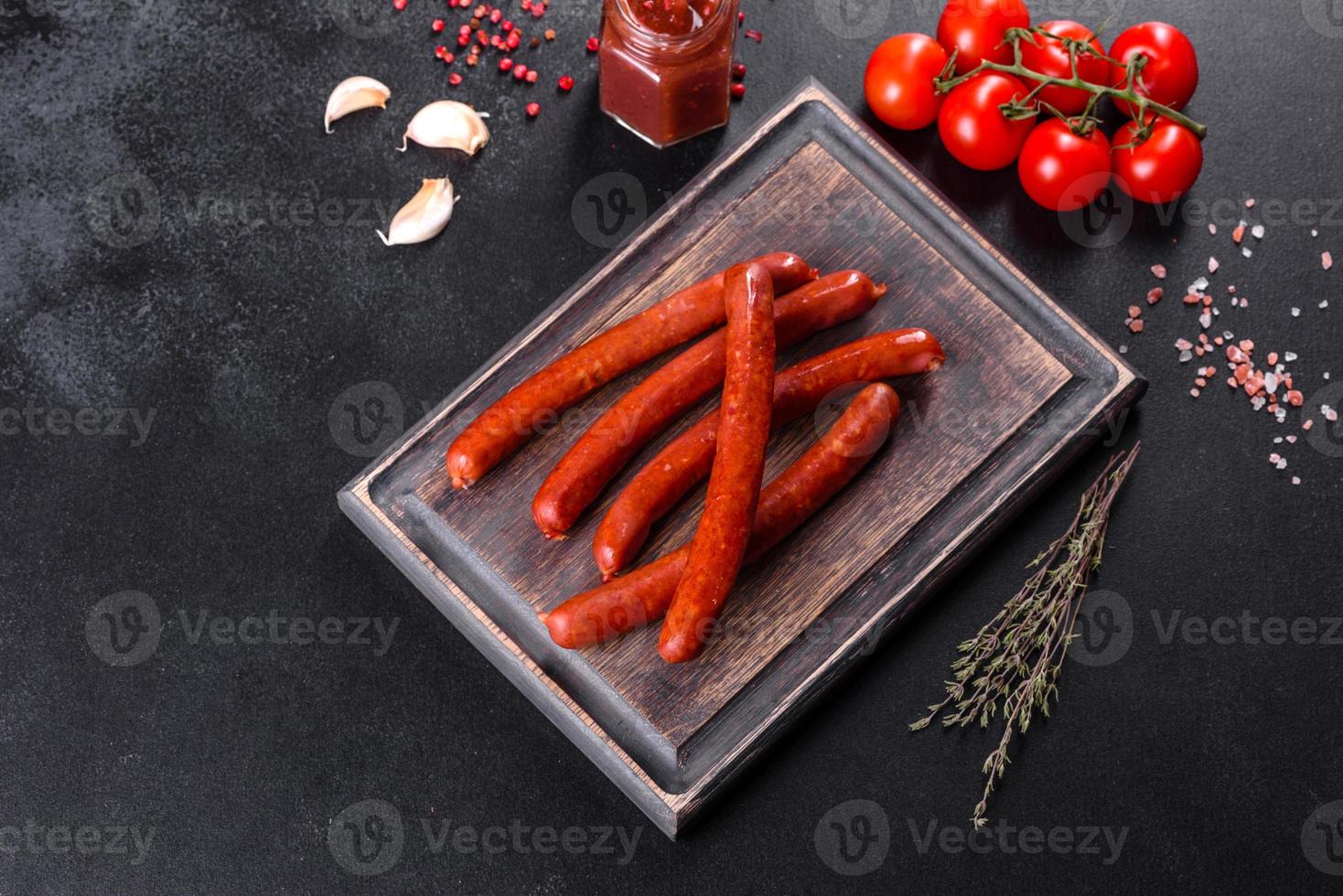 Delicious fresh bright smoked hot sausages with cherry tomatoes and tomato sauce photo