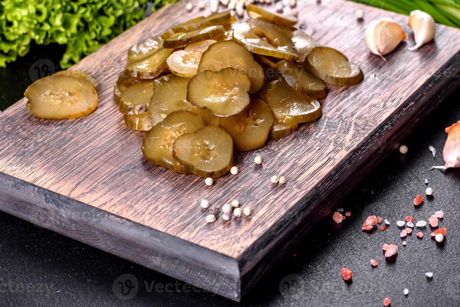 Tasty salty spicy pickled cucumber cut with rings on a wooden cutting board photo