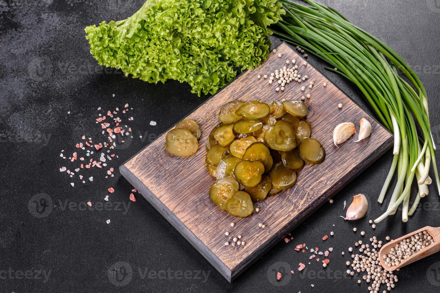Tasty salty spicy pickled cucumber cut with rings on a wooden cutting board photo