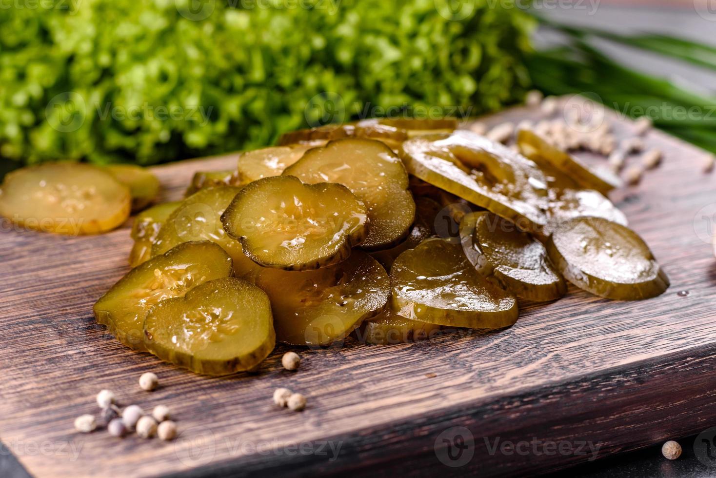 Tasty salty spicy pickled cucumber cut with rings on a wooden cutting board photo