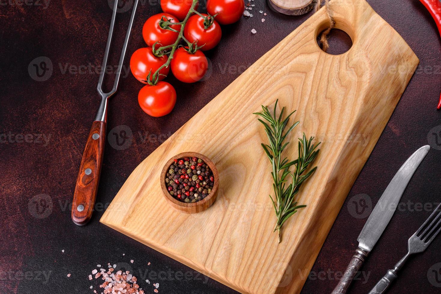 Cutting board with salt, spices and herbs on a dark concrete background photo