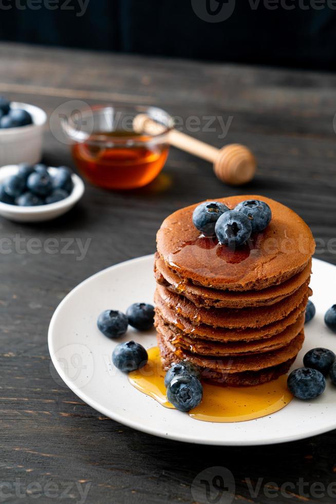 Chocolate pancake stack with blueberry and honey on a plate photo